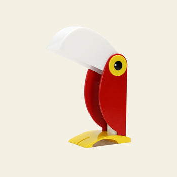 The DETAIL Toucan Lamp by DETAIL features vintage charm with a white beak-shaped shade, red body, yellow base and eye details, displayed against a plain light background.