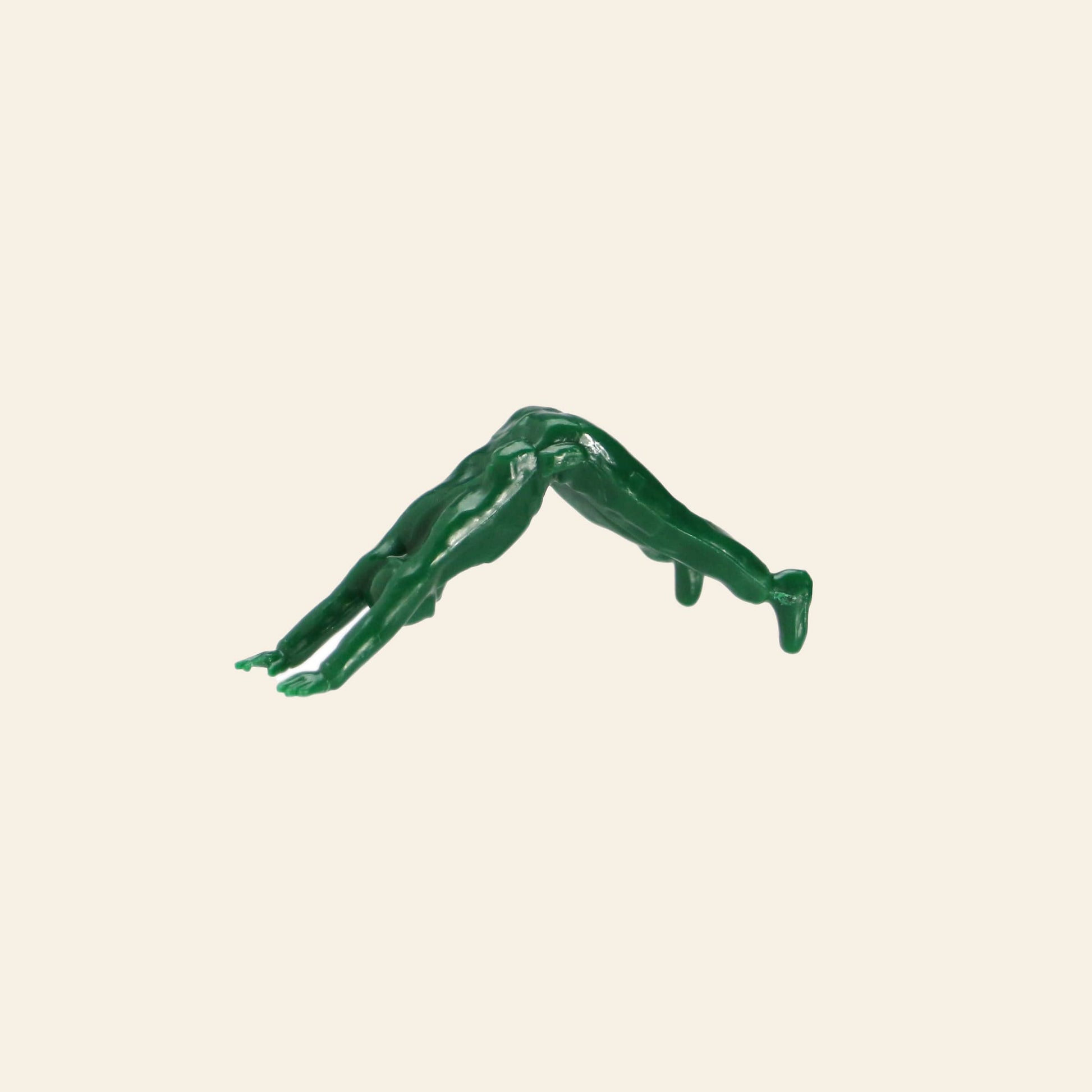 A small green figure from the DETAIL Yoga Joes 9 Figures set by DETAIL is posed in a yoga bridge position, hands and feet on the ground, body arched upward against a plain beige background.