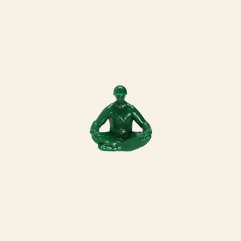 A green plastic DETAIL Yoga Joes 9 Figures toy by DETAIL is shown cross-legged in a meditative pose against a plain beige background.