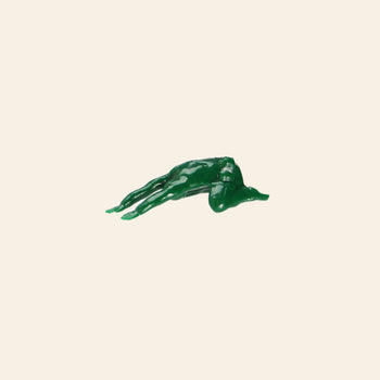 A green plastic DETAIL Yoga Joes 9 Figures toy from DETAIL, inspired by soldier figurines, lies face down on a plain light beige background with arms and legs extended.
