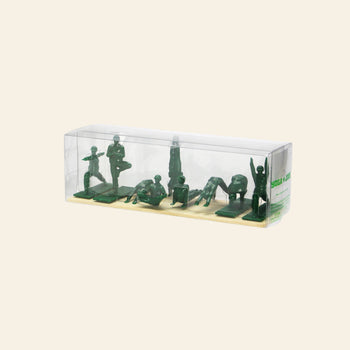 A clear plastic box showcases DETAIL Yoga Joes 9 Figures by DETAIL—green yoga figurines styled like toy soldiers, each striking a pose on a beige base against a plain light background.