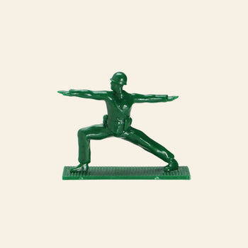 A DETAIL Yoga Joes 9 Figures toy by DETAIL shows a green plastic soldier in a yoga warrior pose, arms extended and legs apart, standing on a textured rectangular base.