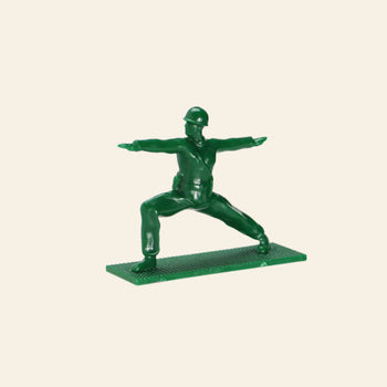 A DETAIL Yoga Joes figure from the 9-piece set by DETAIL strikes a yoga warrior pose on a rectangular base, displayed against a plain beige background.