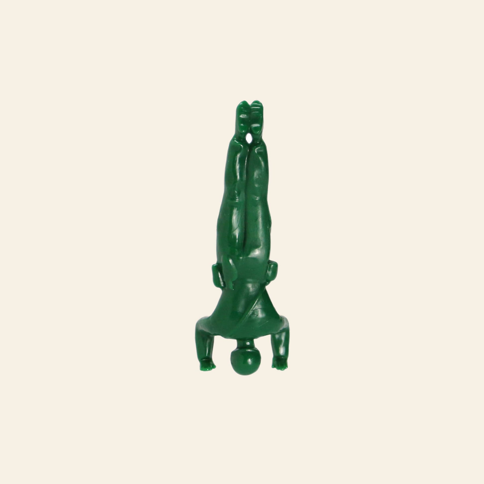 A DETAIL Yoga Joes figure from the DETAIL Yoga Joes 9 Figures set, made of green plastic, does a headstand with arms bent and legs together on a plain beige background.