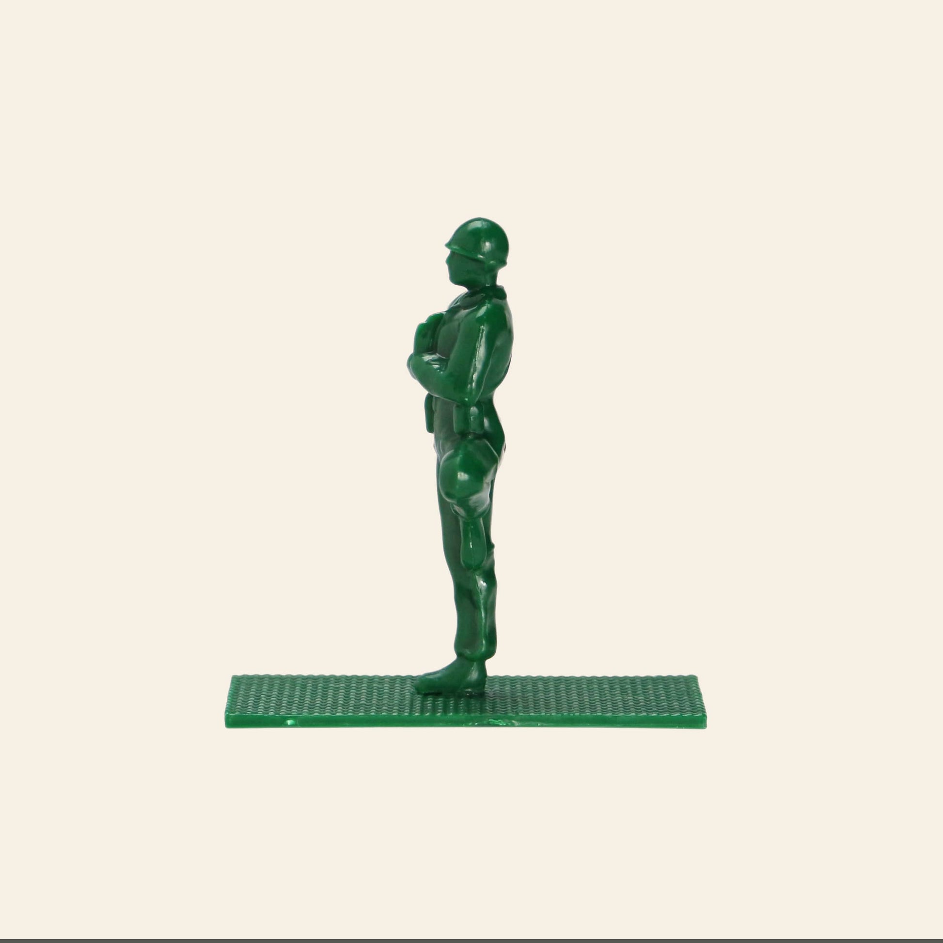 A DETAIL Yoga Joes 9 Figures green plastic toy soldier by DETAIL stands upright on a rectangular base, facing left, set against a plain off-white background.
