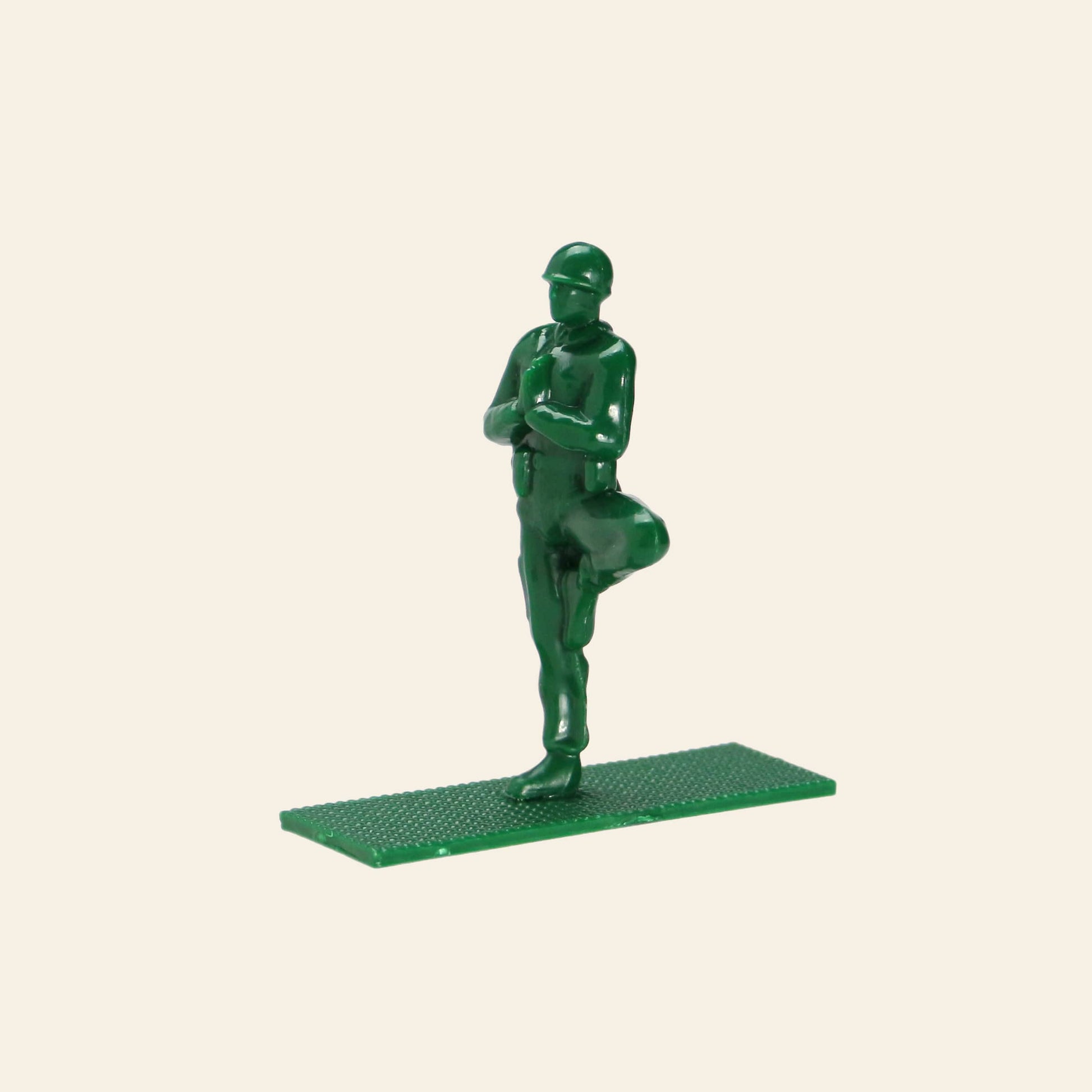 A DETAIL Yoga Joes soldier figure by DETAIL, made of green plastic, stands in the yoga tree pose with arms folded and one foot on the opposite leg atop a rectangular base, shown against a plain beige background. Part of the 9 Figures set.