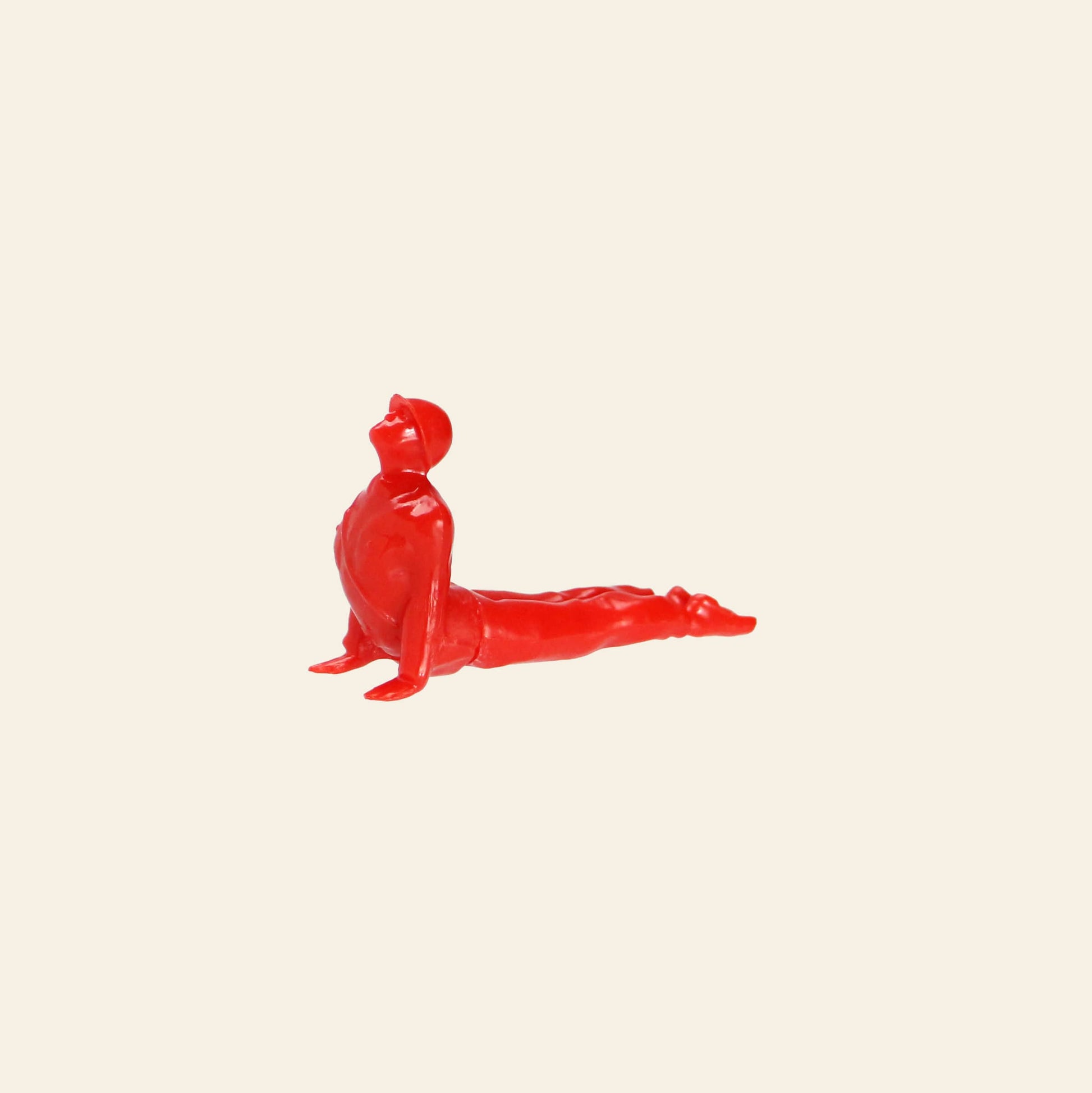 A small red DETAIL Yoga Joes 9 Figures figurine by DETAIL, posed in upward-facing dog, is shown against a plain beige background.