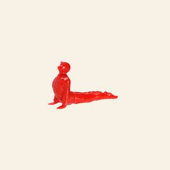 A small red DETAIL Yoga Joes 9 Figures figurine by DETAIL, posed in upward-facing dog, is shown against a plain beige background.
