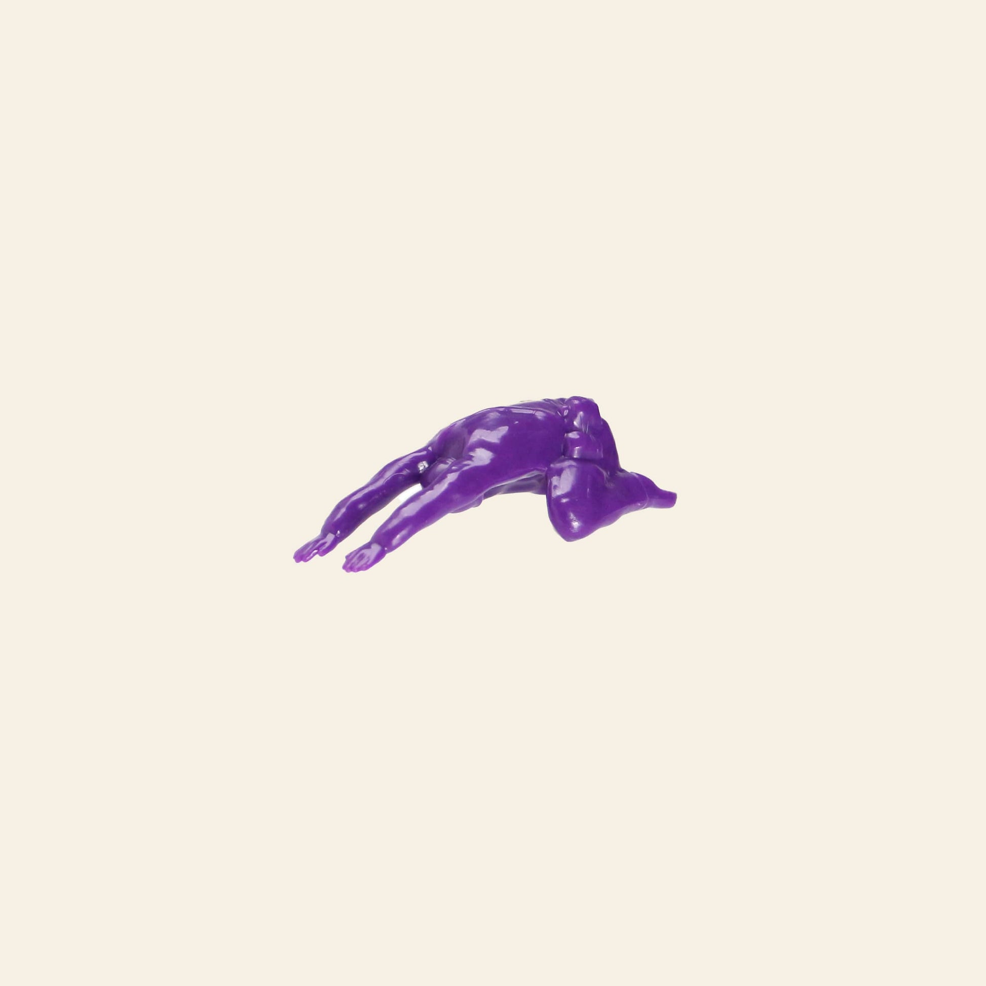 A glossy, purple, human-like figure from the DETAIL Yoga Joes 9 Figures set by DETAIL lies face down on a plain beige background, arms and legs extended in a playful twist inspired by toy soldiers yoga.