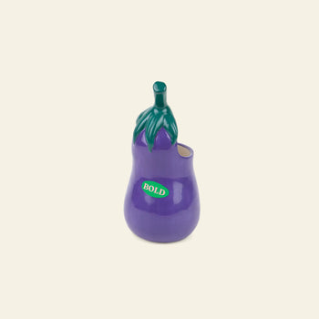 The DOIY Farmers’ Market Eggplant Utensils Pot by DOIY is a ceramic vase shaped like a purple eggplant with green stem and leaves—ideal as an utensil holder or quirky vegetable-themed kitchen decor.