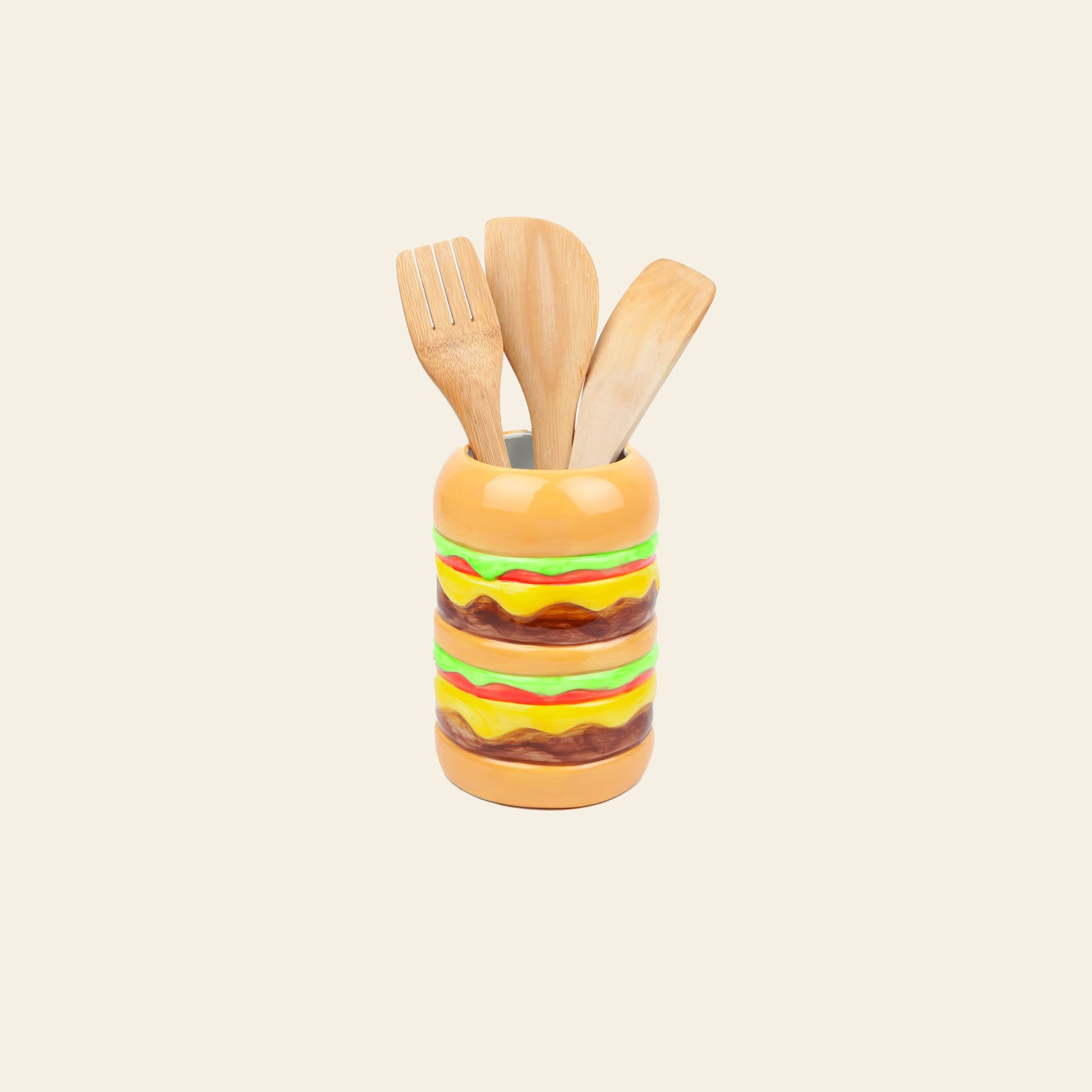 The DOIY Fast Food Burger Vase by DOIY is a ceramic holder shaped like a hamburger and comes with three wooden kitchen utensils—two spatulas and one fork—displayed against a plain cream background.