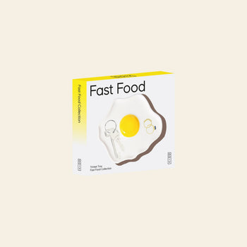 A yellow and white DOIY Fast Food Fried Egg Trinket Tray box with a retro design and fried egg image contains a keychain and two rings arranged like an egg, displayed against a plain light background.