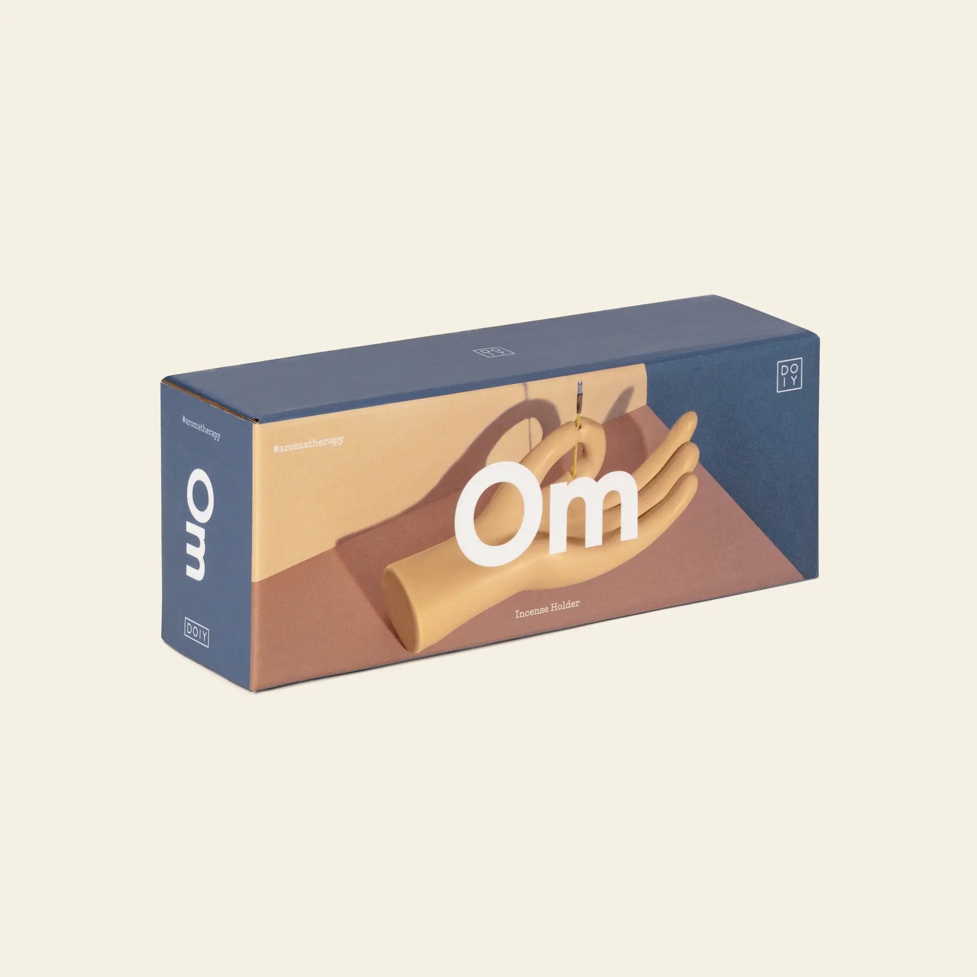 A rectangular blue and beige DOIY Om Meditation Hand Incense Holder box displays the elegant hand-shaped holder cradling an incense stick, with branding by DOIY, set against a plain light background.
