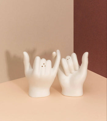 The DOIY Pinky Swear Salt and Pepper Set features ceramic shakers shaped like hands making the shaka and pinky promise gestures, adding an artistic touch to your table.