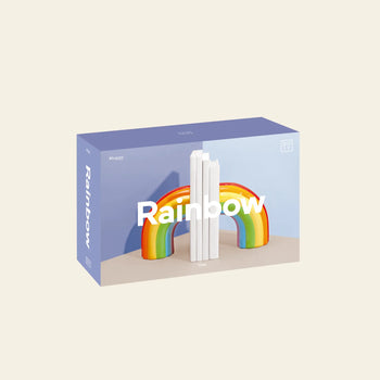 The DOIY Rainbow Bookend features a pastel box with vibrant colors, a 3D rainbow arch, and three upright white books. Rainbow appears on the packaging, highlighting DOIYs bookend as stylish home decor.