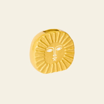 The DOIY Sun Vase by DOIY is a small, round, yellow ceramic vase with a stylized sun face featuring etched eyes, nose, mouth, and radiating sunrays—perfect for brightening your home decor.