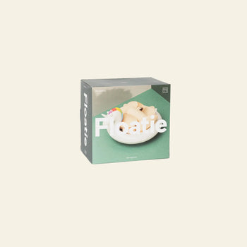 The DOIY Unicorn Floatie Bowl box shows a beige figure relaxing on a unicorn pool float in a pool with a green background and bold white text—a playful decorative accent from DOIY for any space.