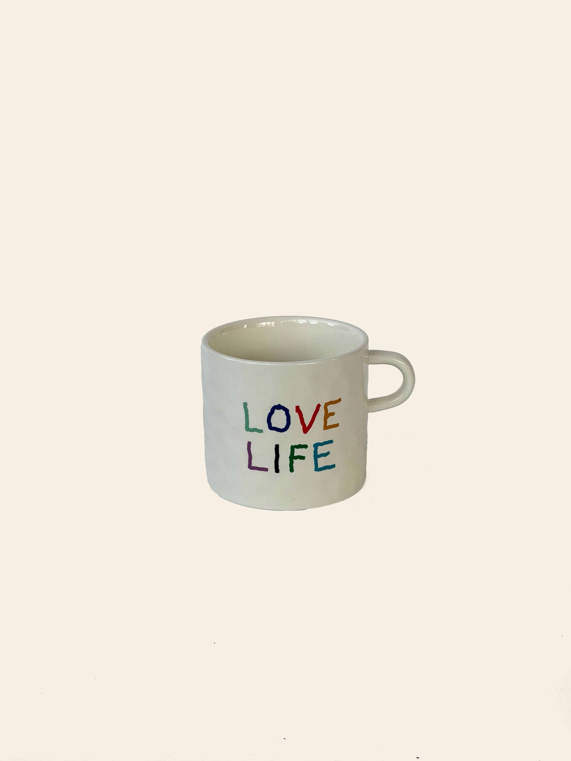 The David Hockney Love Love Mug by David Hockney is a white ceramic mug featuring “LOVE LOVE” in colorful, handwritten letters on the side. Set against a plain, light background, its vibrant and artistic design adds a touch of flair to your daily routine.