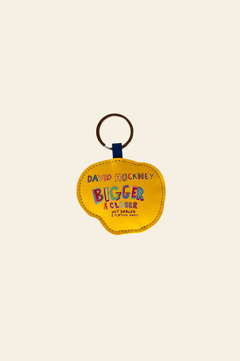 Add a pop of color to your collection with the David Hockney Bigger & Closer Keychain—a yellow speech bubble-shaped accessory featuring vibrant, multicolored text inspired by the iconic exhibition. This official David Hockney keychain is a perfect souvenir for any art enthusiast.