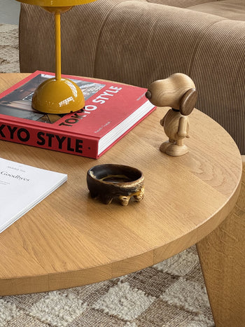 The Dinosaur Designs Crown Dish by Dinosaur Designs, with its glossy, marbled surface and sculptural form, sits centered on a plain beige background, evoking the artistry for which the brand is renowned.