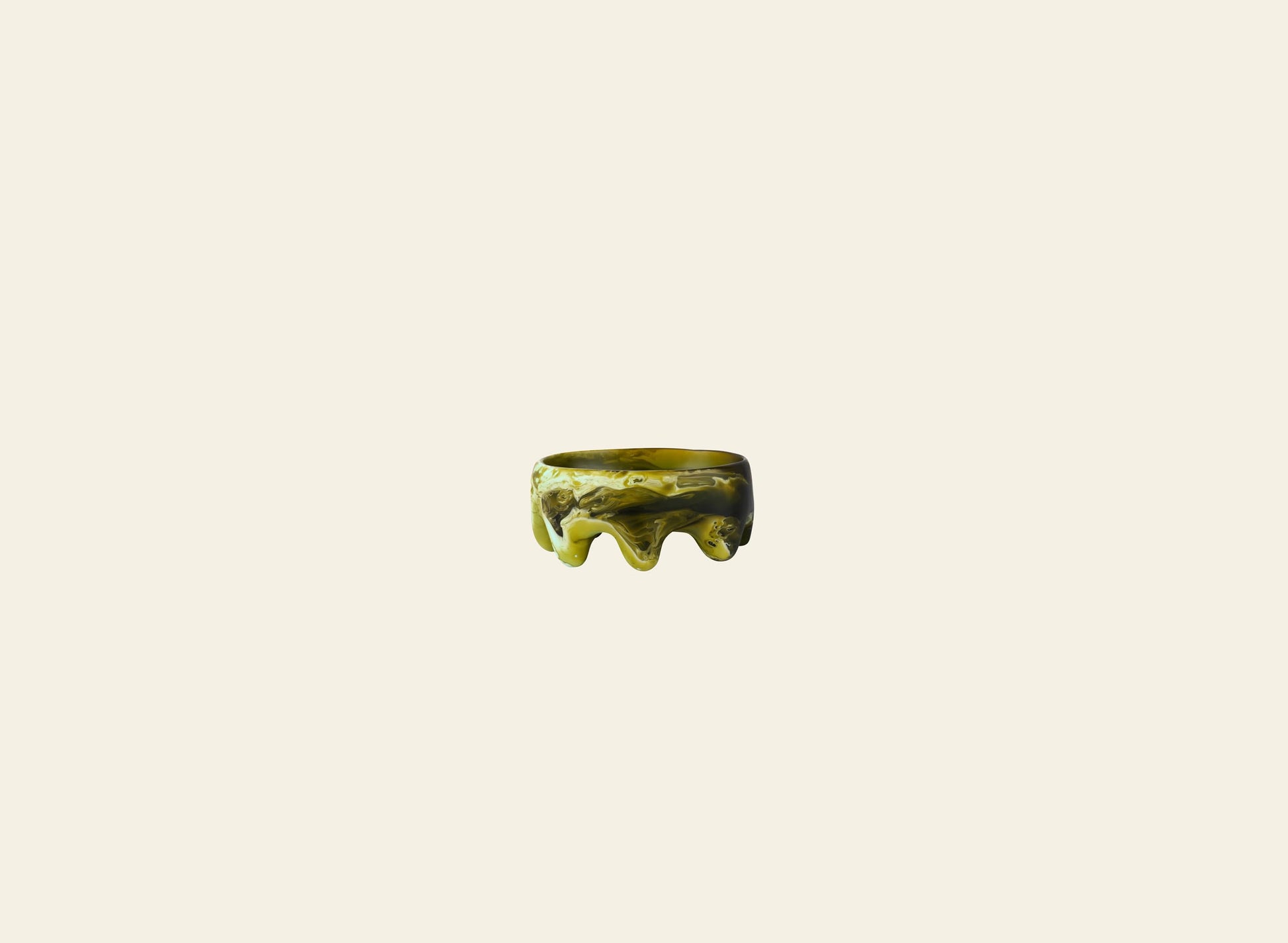 A sculptural Dinosaur Designs Crown Dish in marbled green with a glossy, wavy texture is showcased against a plain beige background.