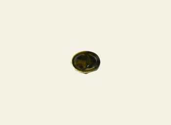 A small, circular swirl of dark green liquid rests at the center of a plain light cream surface, echoing the sculptural elegance of the Dinosaur Designs Crown Dish by Dinosaur Designs.
