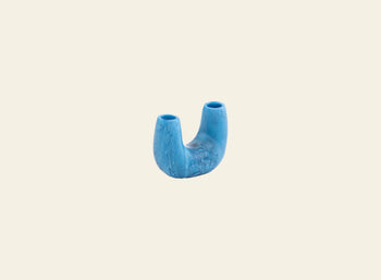 A blue, U-shaped Dinosaur Designs Mini Branch Vase with two openings from the Branch vase collection, displayed on a plain light beige background.
