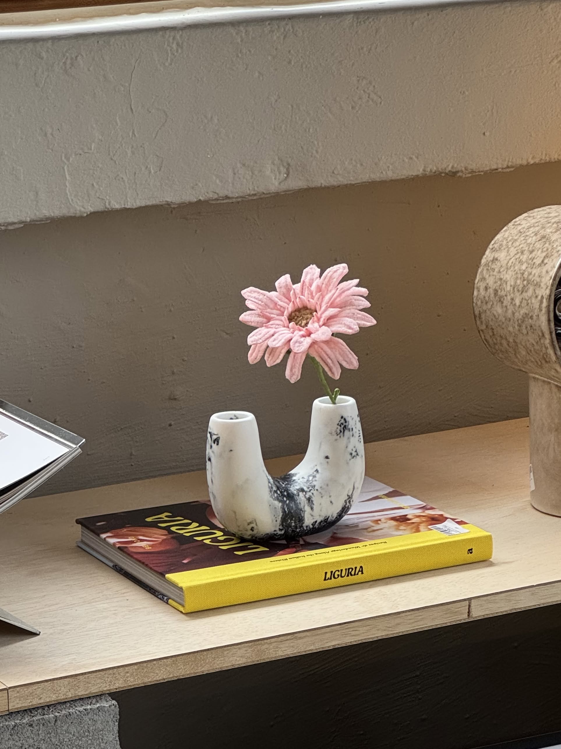 A small, white, U-shaped Dinosaur Designs Mini Branch Vase with a rough texture and black speckles is centered on a plain beige background.