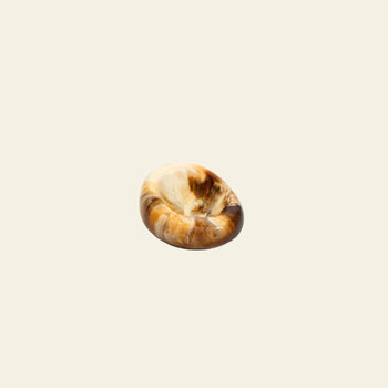 The Dinosaur Designs Small Drift Dish features a small, round shape with swirled brown, tan, and cream tones for an organic feel, shown against a plain beige background.