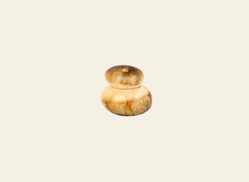 The Dinosaur Designs Small Pebble Jar, a handmade, sculptural two-tiered piece crafted from light marbled wood, sits centered on a plain cream background.