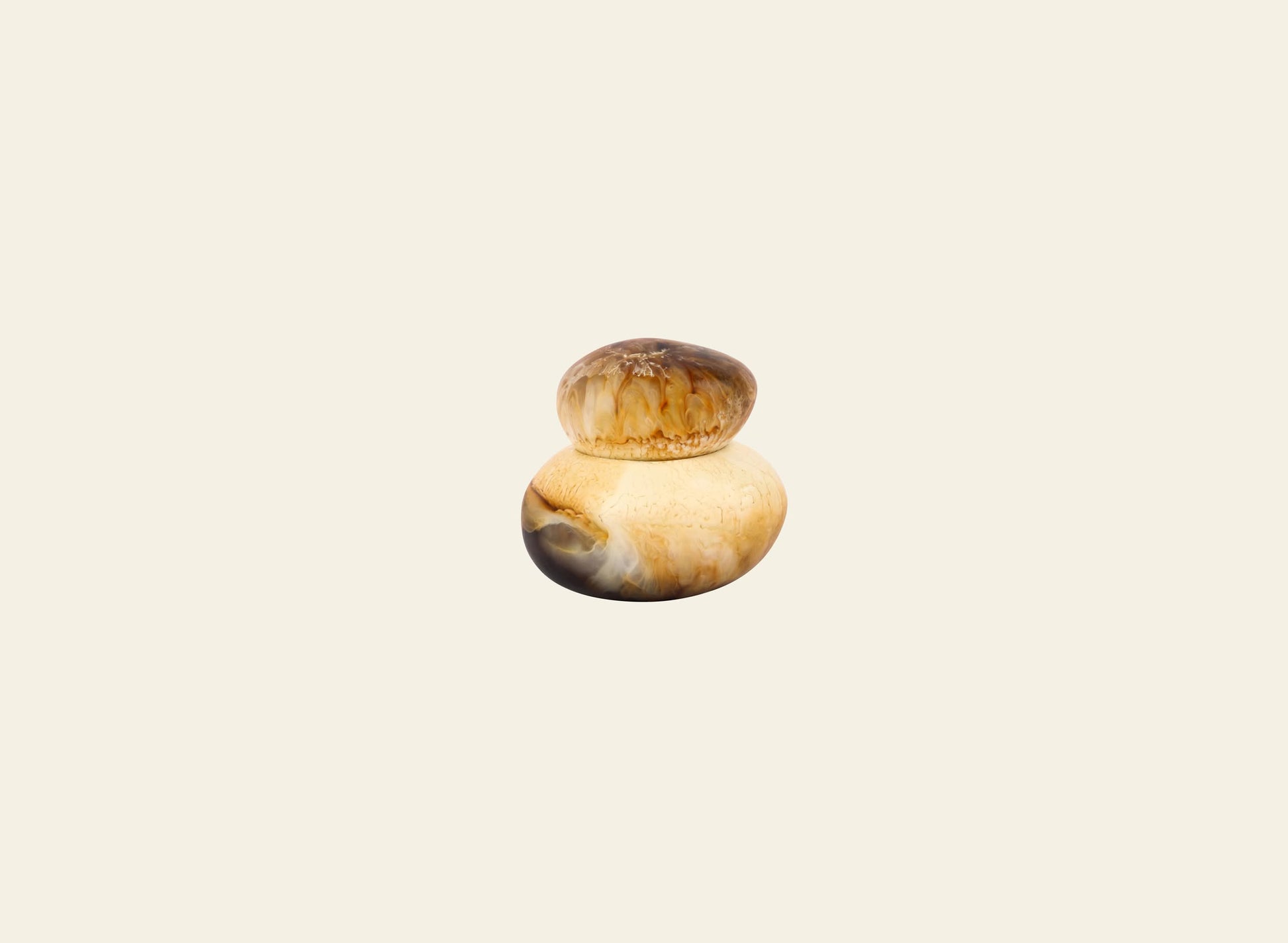 The Dinosaur Designs Small Pebble Jar by Dinosaur Designs features a sculptural design with two smooth, round stones—a light beige and brown gradient base and a handmade, smaller top stone in deeper brown tones.