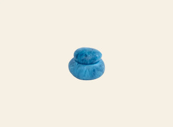 The Dinosaur Designs Small Pebble Jar by Dinosaur Designs features a small, round blue shape with marbled patterns, resembling two stacked pebbles—ideal for stylish storage and displayed on a plain beige background.