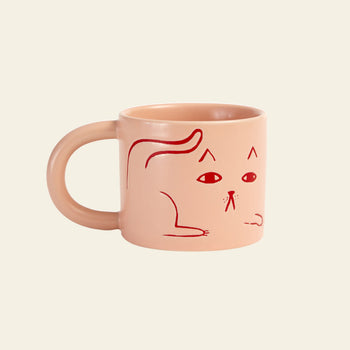 The Donna Wilson Cat Mug by Donna Wilson features a light pink design with a simple red line cat illustration and a neutral expression on an off-white background—perfect for your coffee break.