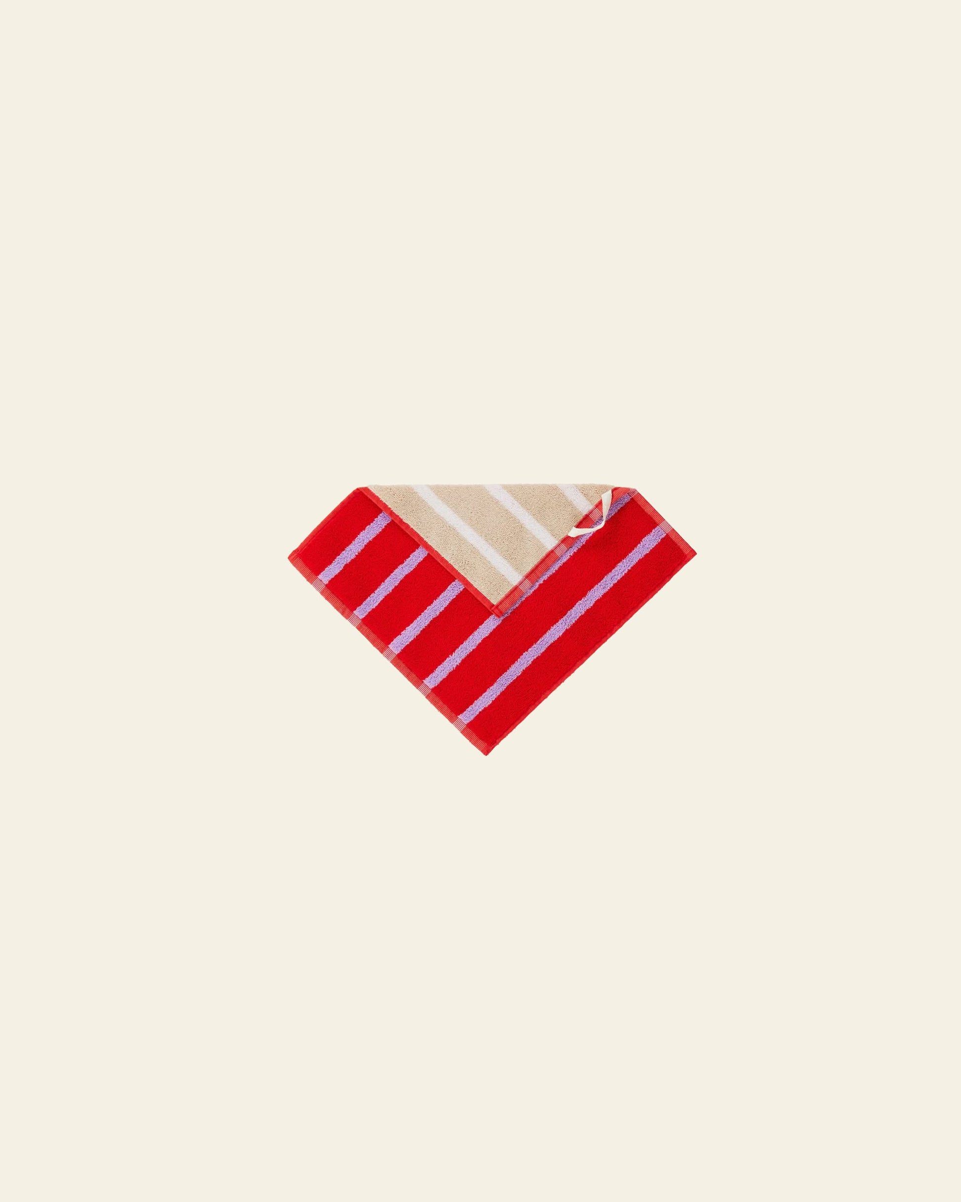 The Dusen Dusen House Stripe Porcelain Washcloth by Dusen Dusen features beige and white stripes on one side, red and white stripes on the other, and a vibrant striped design, shown folded on a plain light background.