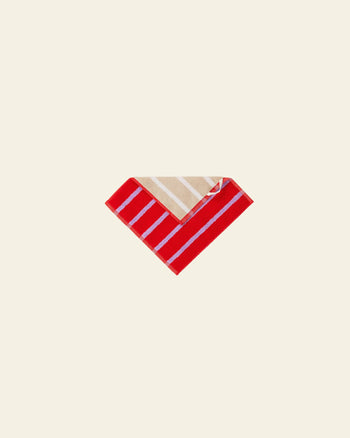 The Dusen Dusen House Stripe Porcelain Washcloth by Dusen Dusen features beige and white stripes on one side, red and white stripes on the other, and a vibrant striped design, shown folded on a plain light background.