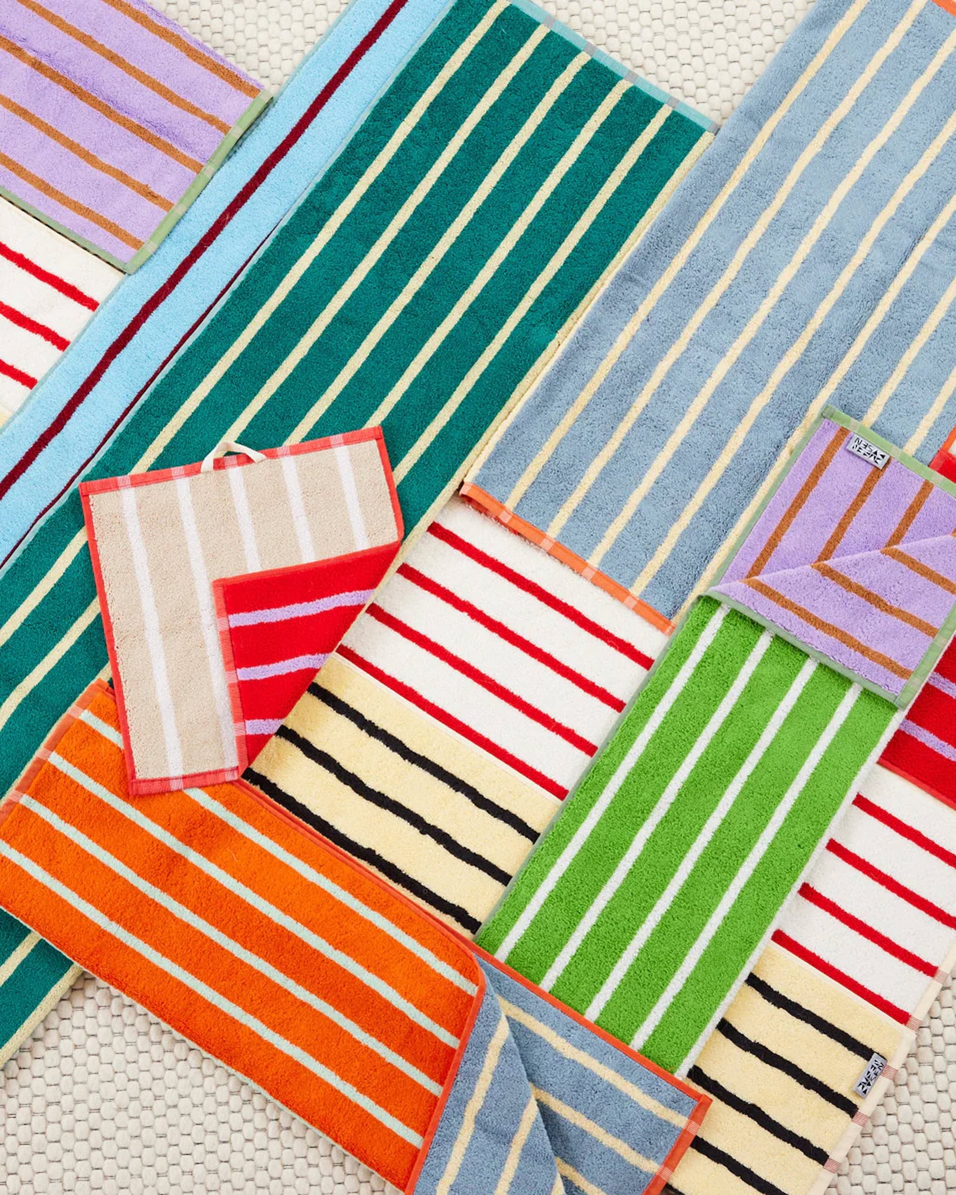 The Dusen Dusen House Stripe Tile Bath Towel features bold stripes of vibrant green, blue, orange, purple, and red on soft cotton terry, adding a colorful touch to your bath routine.