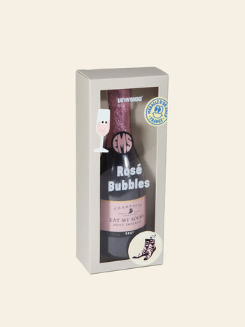 Presented in a gift box designed to resemble a bottle of rosé champagne, Eat My Socks Rosé Bubbles Socks by Eat My Socks feature an abstract pink unisex sock pattern. The playful packaging, decorated with illustrations of a wine glass and a sock, makes them a stylish and fun treat for any occasion.