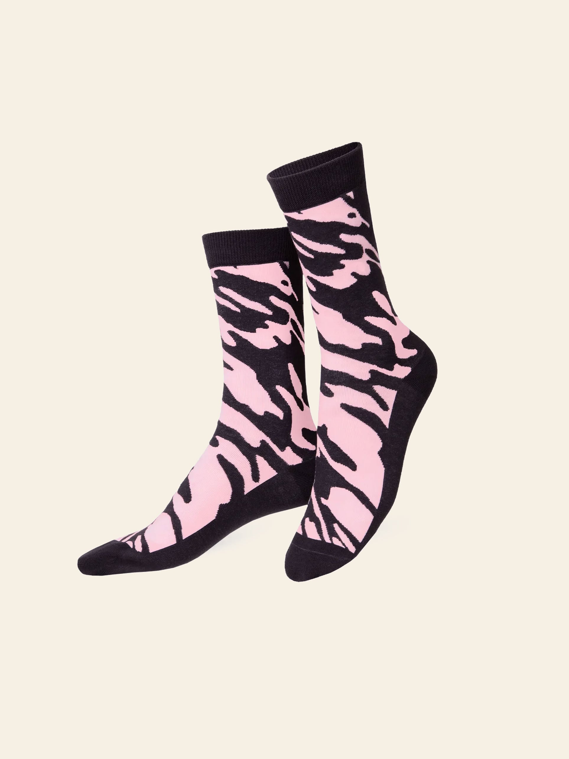Two Eat My Socks Rosé Bubbles Socks by Eat My Socks, featuring a vibrant pink and black zebra stripe pattern with black cuffs, heels, and toes, are displayed on a light beige background.
