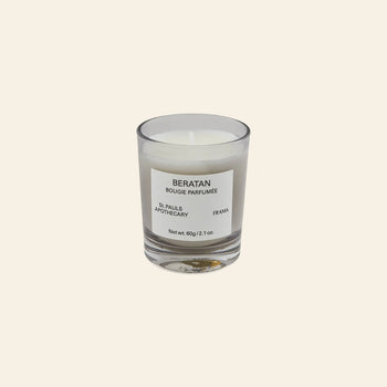 The FRAMA Beratan Scented Candle, 60g, features a clear glass holder with “BERATAN BOUGIE PARFUMÉE, ST. PAULS APOTHECARY, FRAMA” on the label, set against a beige background and offering a warm botanical fragrance.