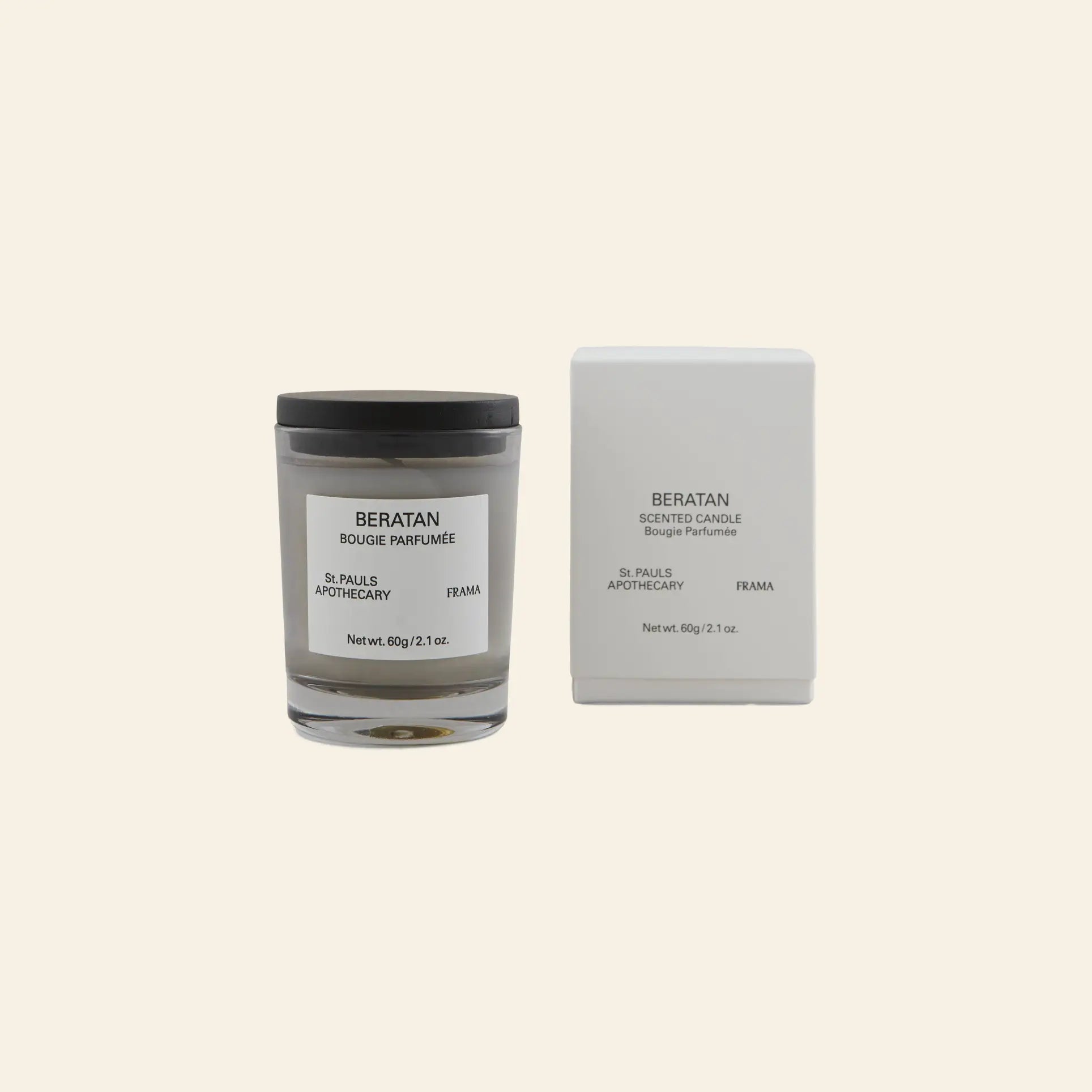 The FRAMA Beratan Scented Candle, 60g, features a glass jar with a black lid and minimalist white label, paired with a matching box—both branded “FRAMA”—offering a botanical, warm fragrance against a beige backdrop.
