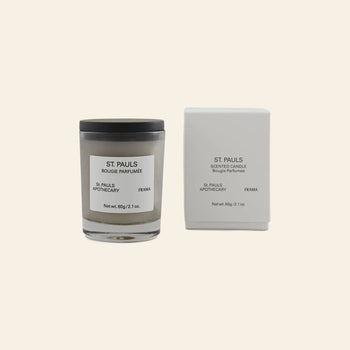 The FRAMA St. Pauls Scented Candle, 60g, sits next to its elegant white box on a beige background, highlighting the brands signature evocative aroma.