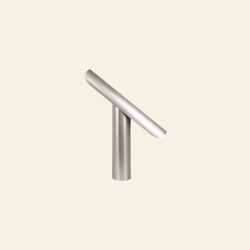The FRAMA T-Lamp Table Lamp by FRAMA features a subtle, minimalist geometric design with brushed metal and clean lines, displayed against a plain, light beige background.