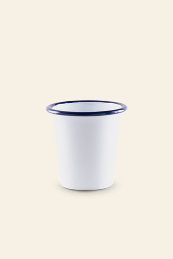 The Falcon Enamelware Tumbler by Falcon Enamelware, featuring a white enamel finish with a wide rim and blue edge for a vintage look, is displayed on a plain light beige background.