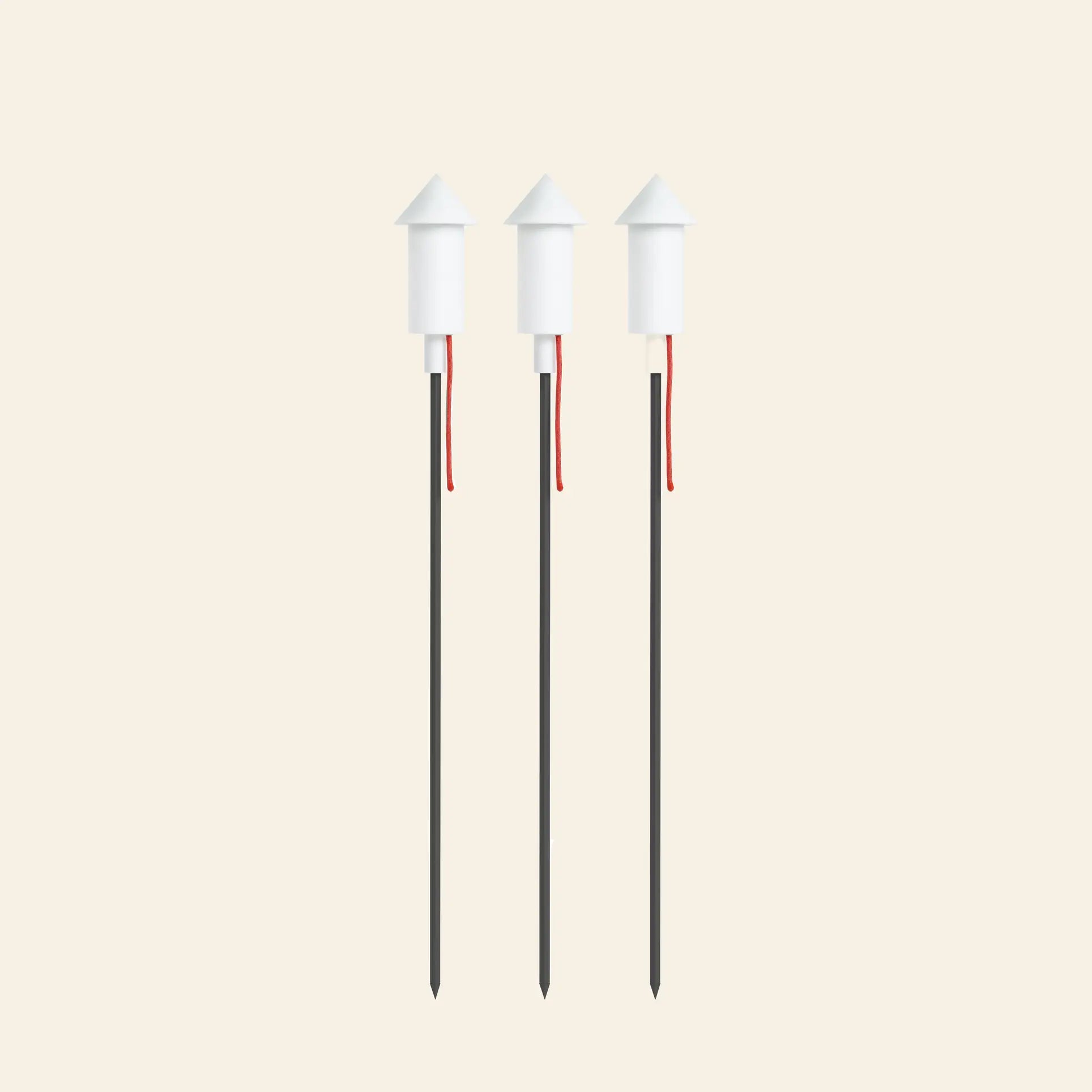 The Fatboy Prêt a Racket Set of 3 by Fatboy features three white rocket-shaped floor lamps with red fuses, arranged upright in a row against a light beige background—perfect for adding playful illumination to any space.