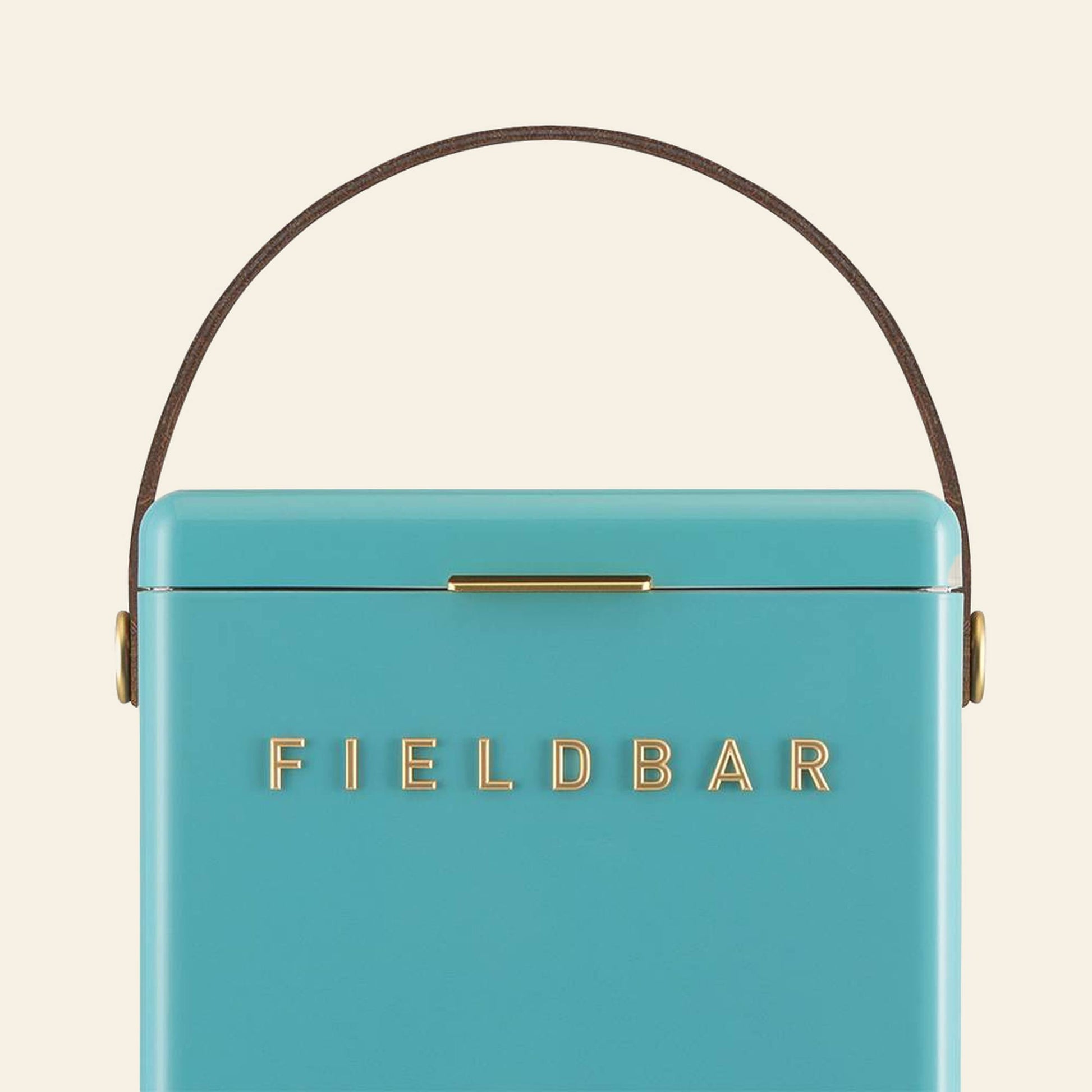 A close-up of the turquoise Fieldbar Drinks Box by Fieldbar, featuring a brown handle and gold FIELD BAR lettering on the front, set against an off-white background.