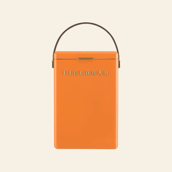 An orange Fieldbar Drinks Box ice box with a brown handle and gold clasp, featuring the gold FIELDBAR logo on the front, is shown against a plain light background.