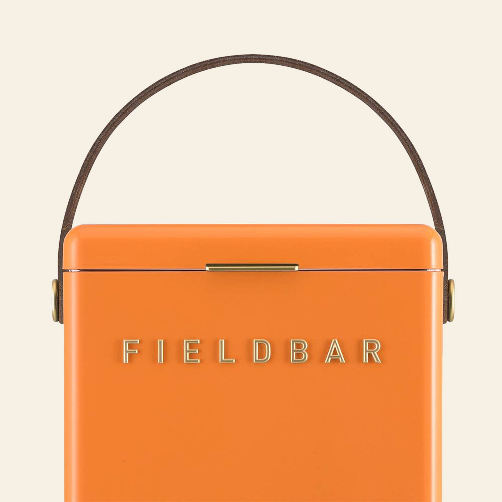 The Fieldbar Drinks Box in orange, featuring gold FIELD BAR branding, a brown handle, and a gold latch, highlights stylish thermal performance by Fieldbar against a plain light background.
