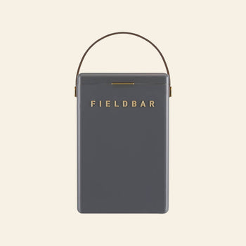 The Fieldbar Drinks Box is a rectangular, dark gray cooler with gold Fieldbar branding and a brown top handle, acclaimed for excellent thermal performance and shown against a light beige background.