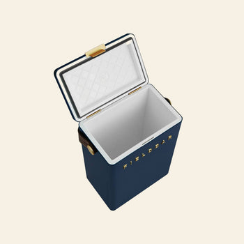 A blue rectangular Fieldbar Drinks Box cooler by Fieldbar with an open white lid, gold latch, and leather handles. FIELD BAR appears in gold on the side. The empty ice box is set against a plain light background.