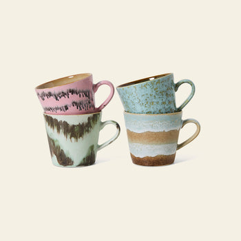 The HKLIVING 70s Ceramics: Cappuccino Mugs, Set of 4 features pink, green, blue, and brown hand-glazed mugs stacked in pairs, blending retro charm with modern style against a simple light background.